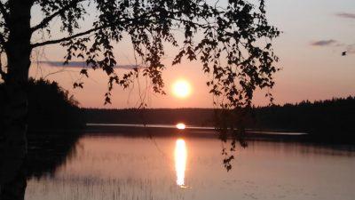 ilta-aurinko laskee järven taakse