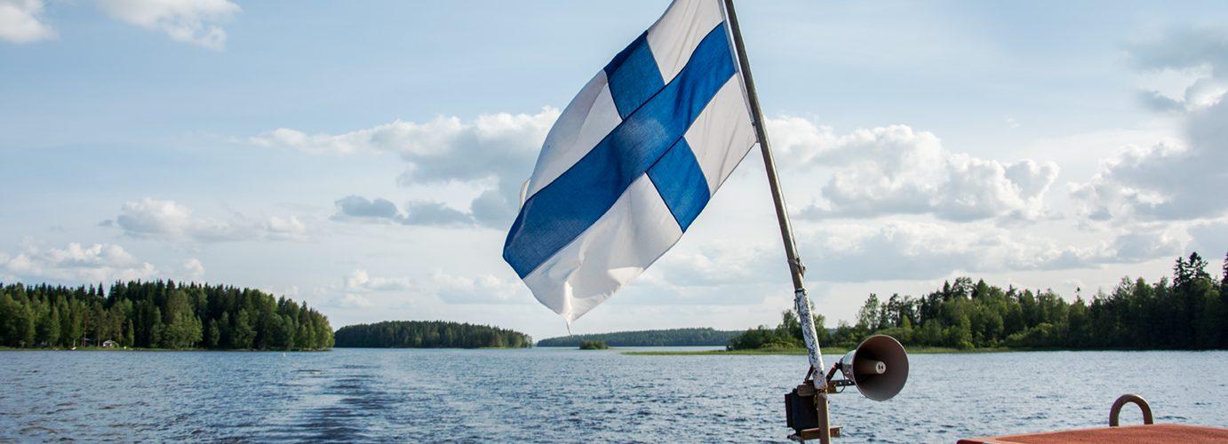 suomen lippu hulmuaa laivan perässä taustalla Keurusselkä järven laineet