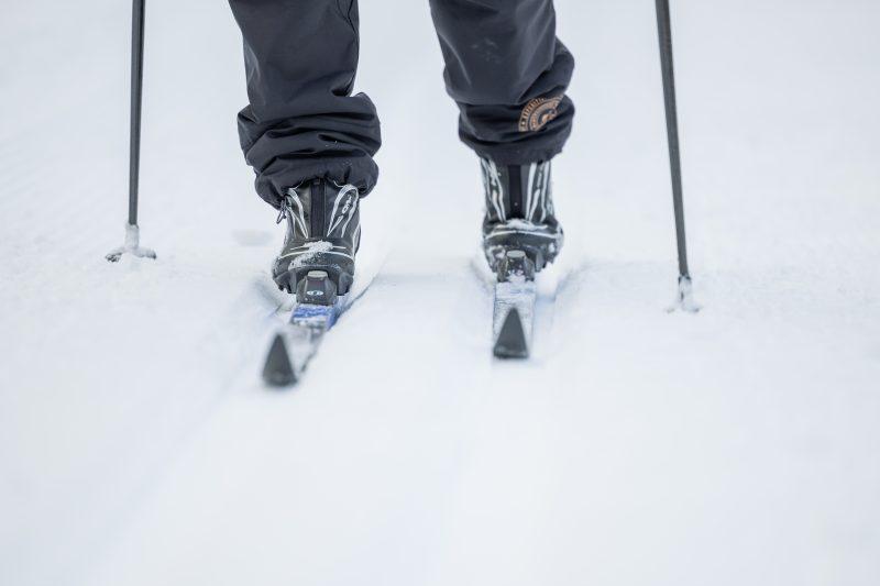 hiihtäjän jalat suksineen ja sauvoineen ladulla